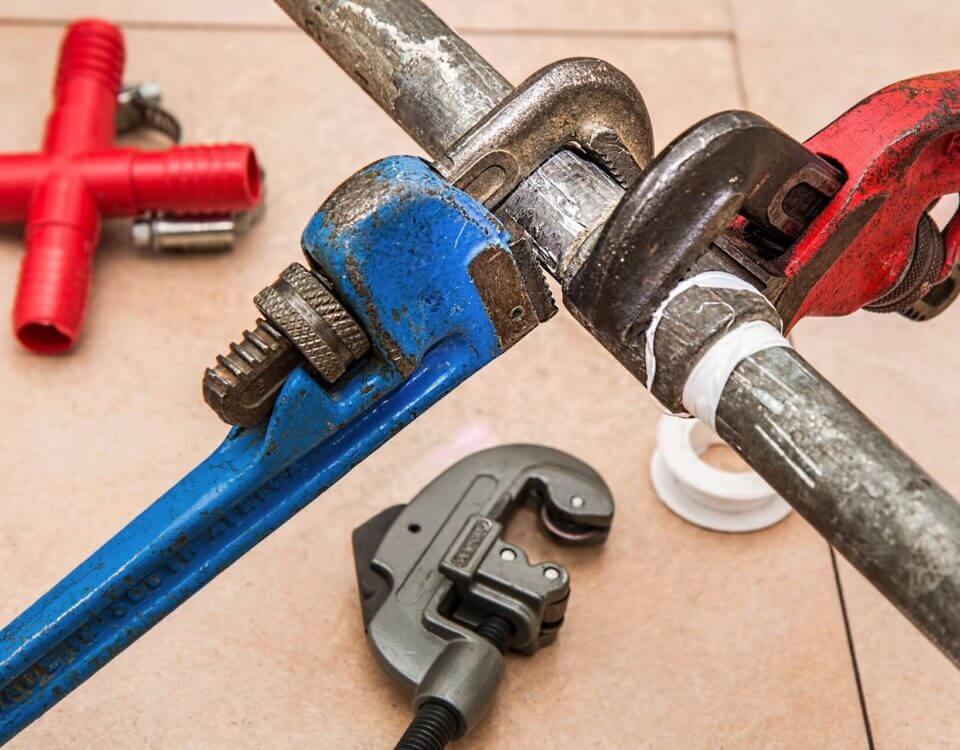 plumber using pipe wrench to repair plumbing pipe connection