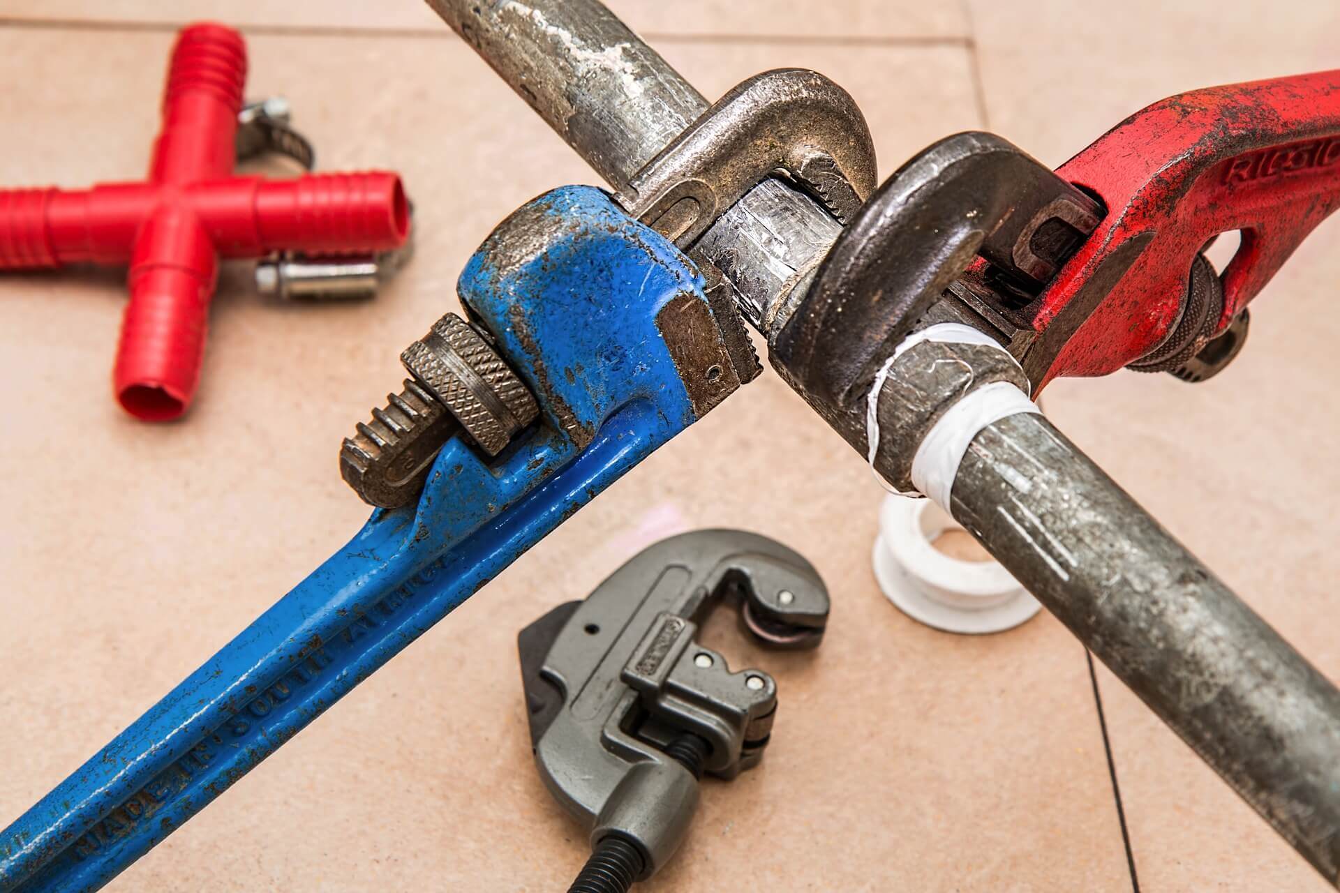 plumber using pipe wrench to repair plumbing pipe connection